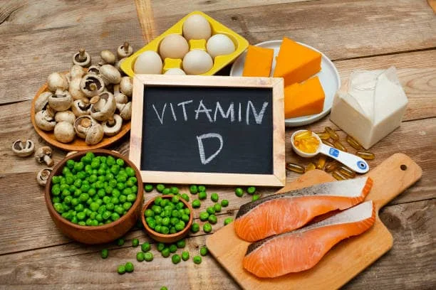 مجموعة من الأطعمة الغنية بفيتامين د مع لوحة مكتوب عليها Vitamin D، توضح أهمية تحليل الفيتامينات في معمل فاليو للتحاليل الطبية