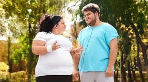 رجل وامرأة يعانيان من السمنة يمارسان الرياضة في الهواء الطلق